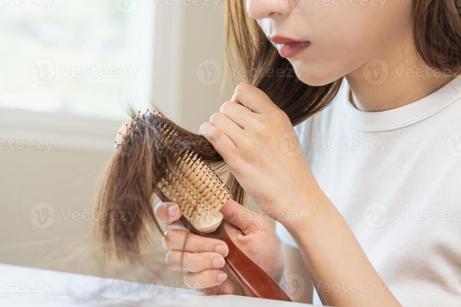 endommagé cheveux, frustré asiatique Jeune femme, fille main dans en portant brosse scission prend fin désordonné tandis que ratissage cheveux, non brossé sec longue cheveux. santé se soucier beauté, portrait isolé sur blanc Contexte. photo