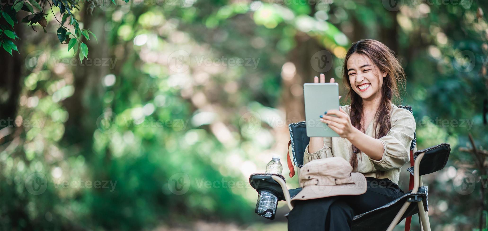 jeune femme utilise un appel vidéo sur tablette en camping dans le parc photo