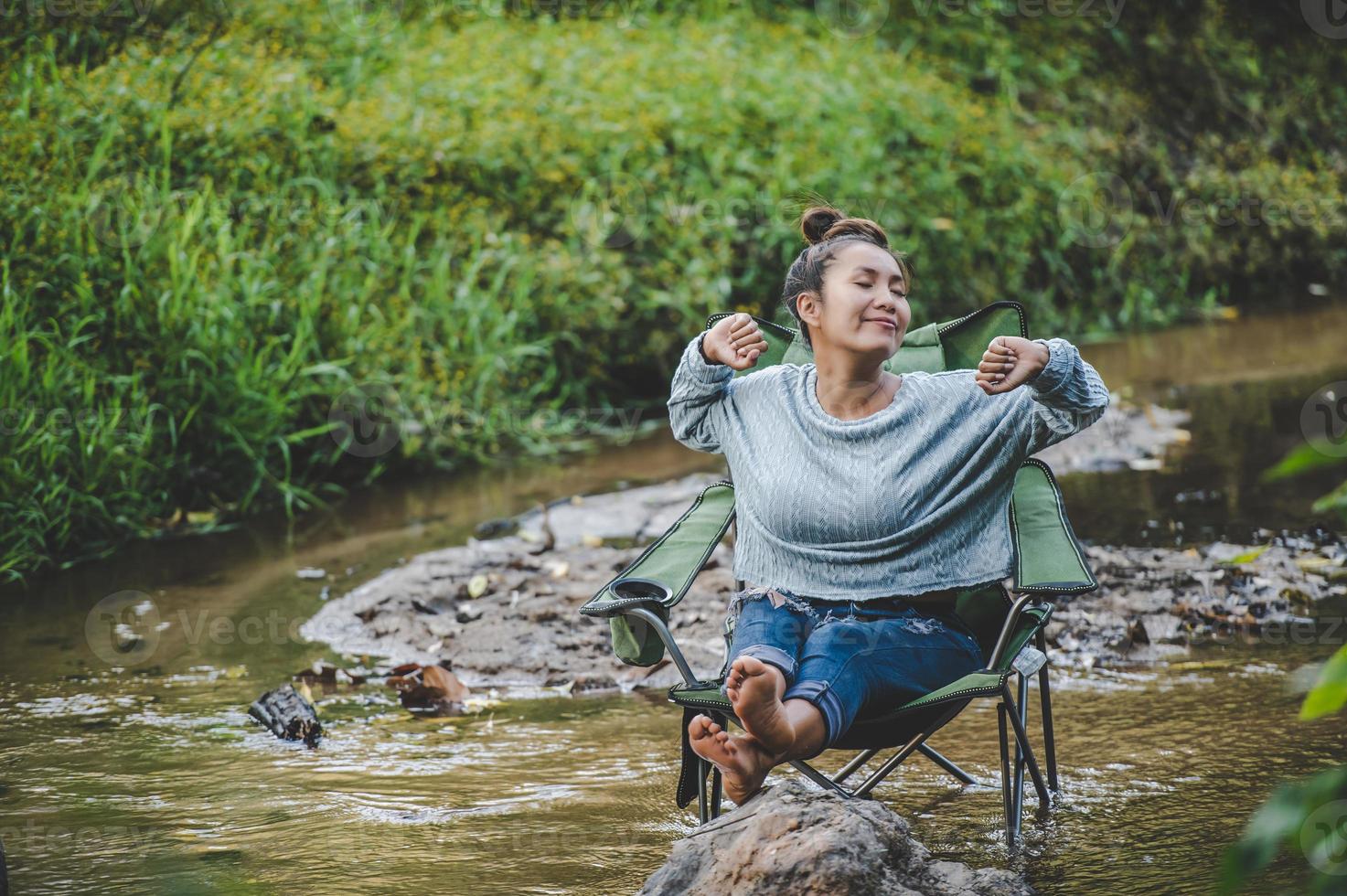 jeune femme assise sur une chaise de camping en ruisseau pour se détendre photo