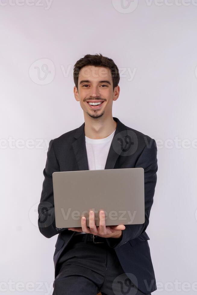 portrait d'un jeune homme d'affaires souriant et beau tenant un ordinateur portable dans les mains, tapant et parcourant des pages Web isolées sur fond blanc photo