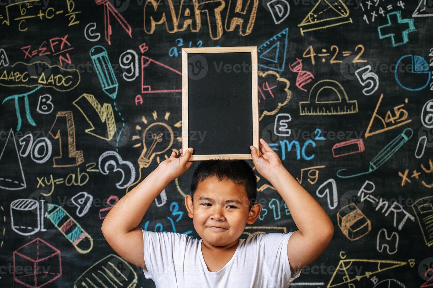 enfant debout et tenant un tableau noir dans la salle de classe photo