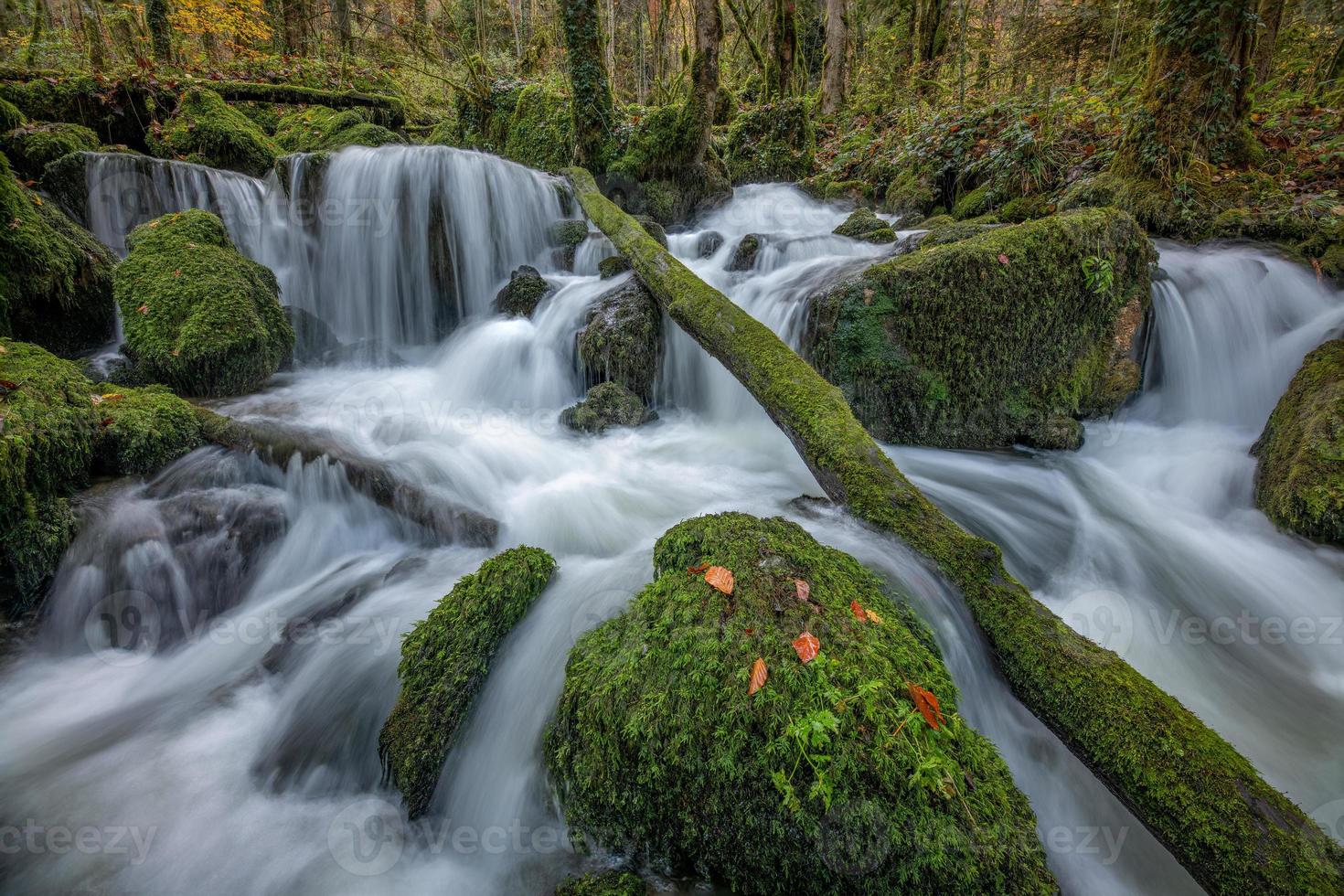 une cascade dont des pierres sont couvert avec mousse photo