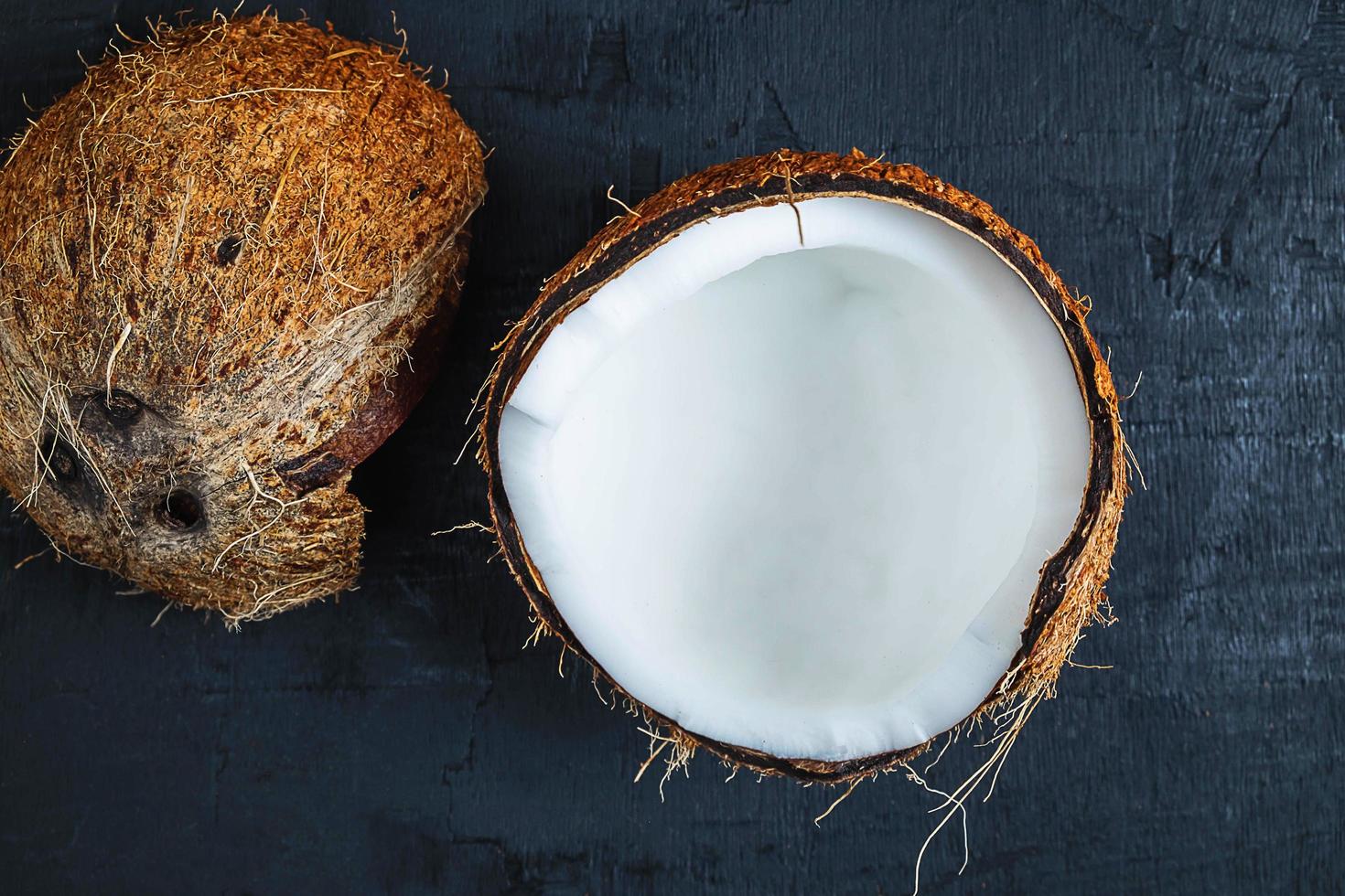 Noix de coco coupée en deux sur un fond de tableau noir photo