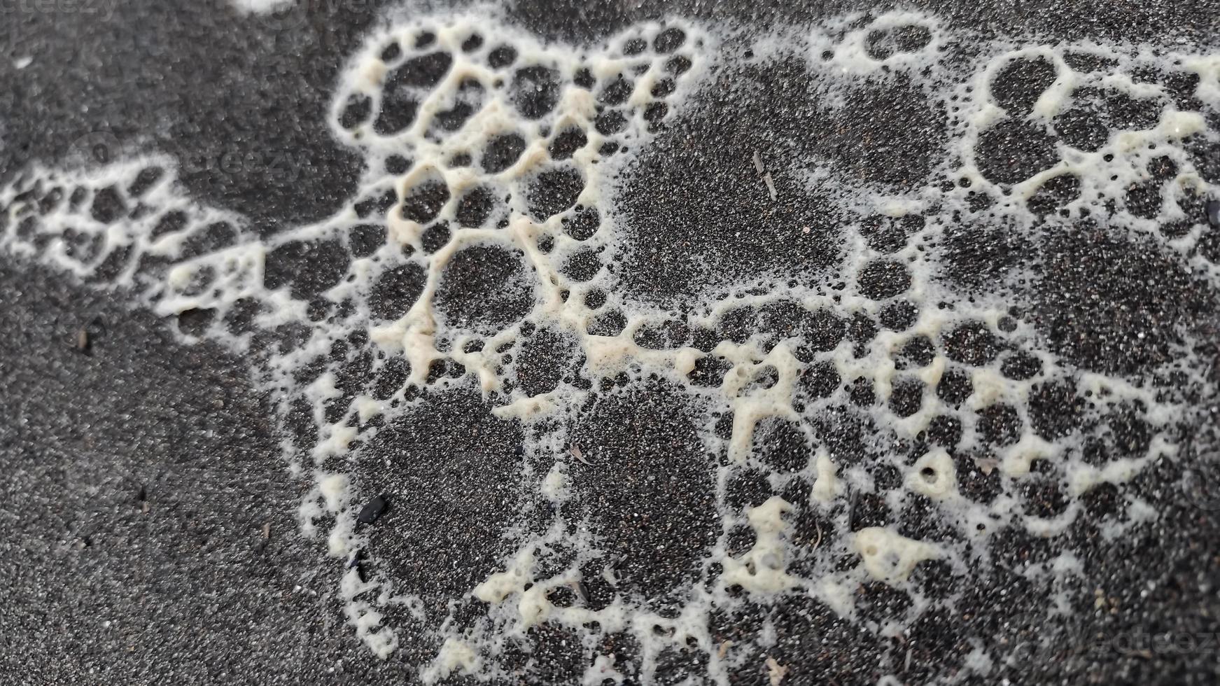 une proche en haut de une noir surface avec blanc mousse et bulles. photo