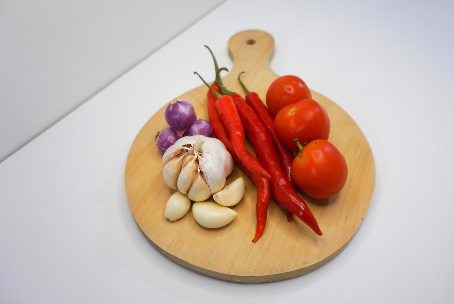 ail, le Chili, rouge oignon et tomates sur une en bois Coaster, haute angle tir. photo