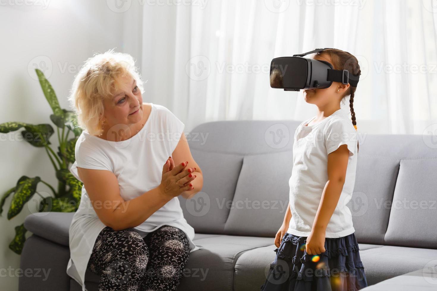 Sénior femme en utilisant virtuel réalité des lunettes avec sa petite fille photo