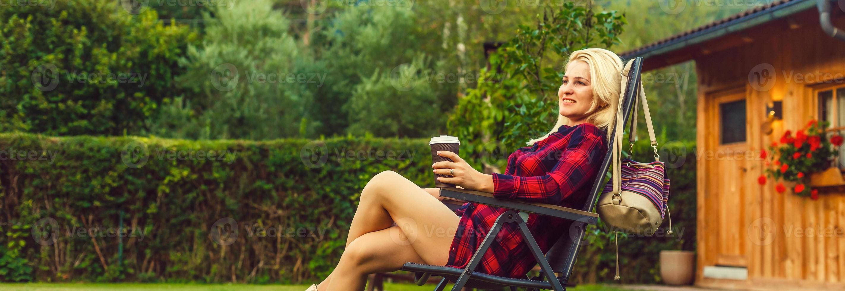 en plein air mode de vie portrait de en voyageant fille en portant une tasse de café. profiter incroyable vue sur le baie. portant à carreaux chemise. de bonne heure Matin. en voyageant et tourisme concept. sentiment liberté photo