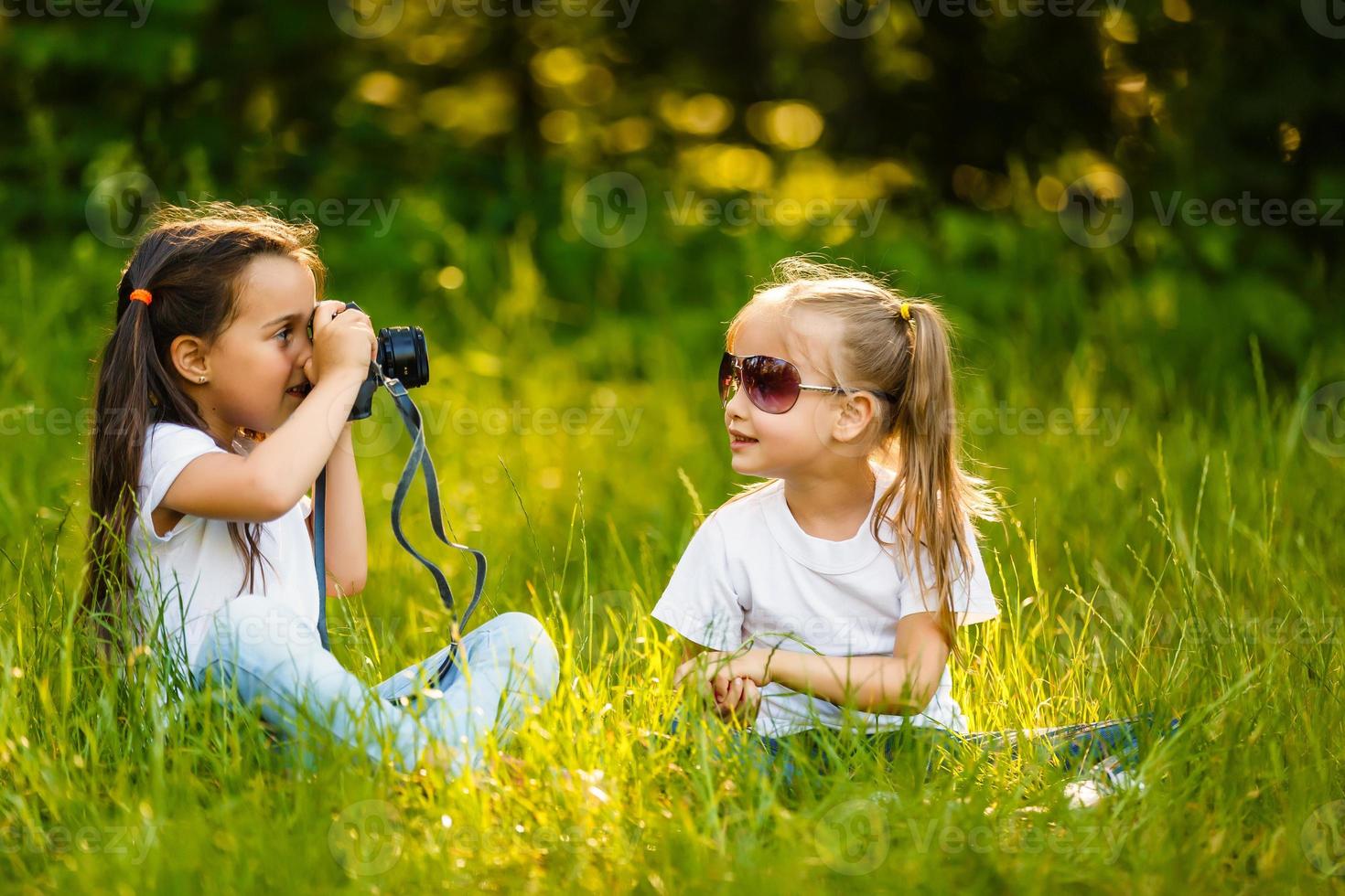 deux les enfants fille tenir une caméra prendre une image chaque autre avec sourire photo