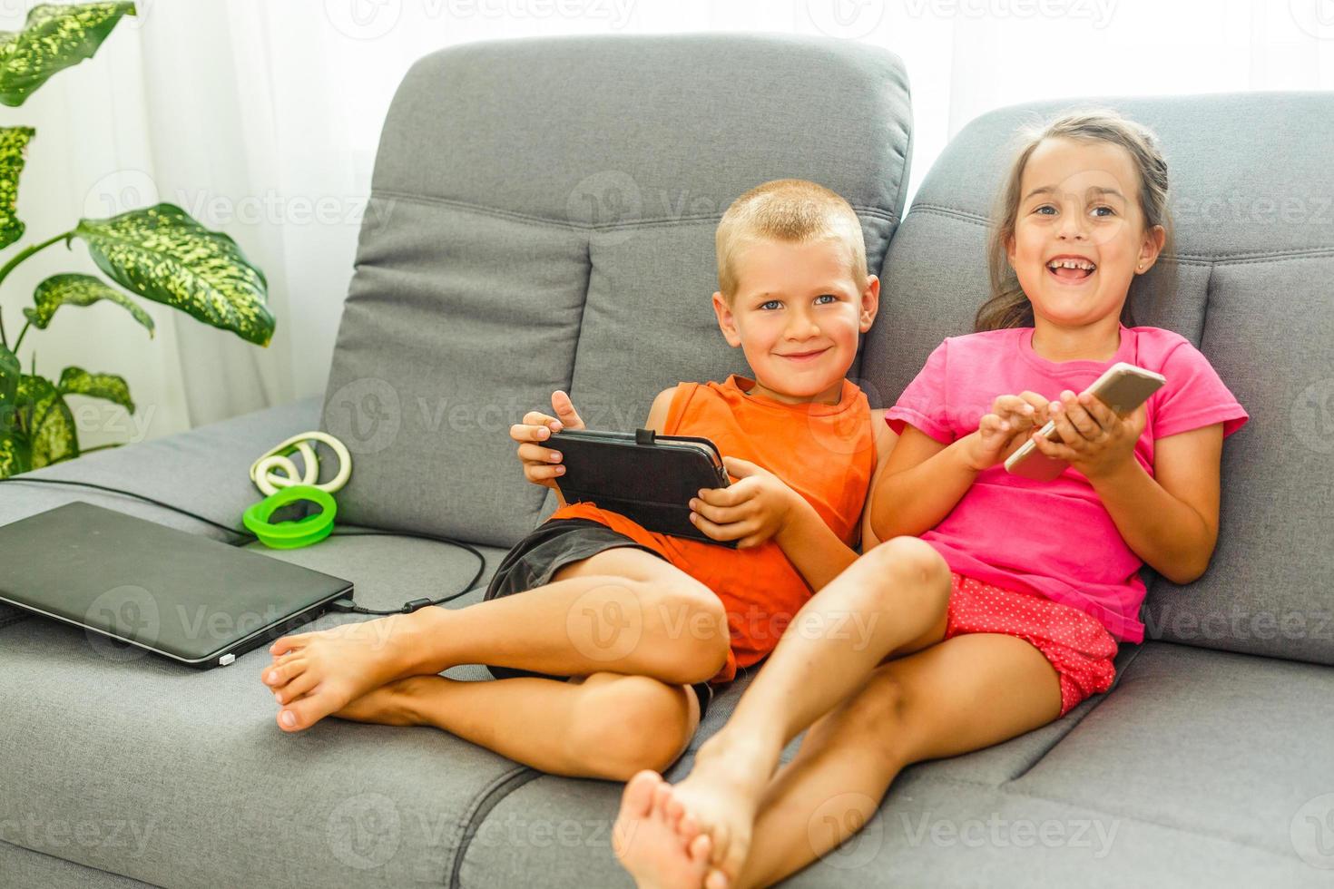 frère et sœur séance sur canapé à Accueil en utilisant mobile téléphone. proche en haut surpris fille et frustré fils à la recherche à dispositif filtrer. La technologie Nouveau génération intoxiqué avec gadgets concept photo