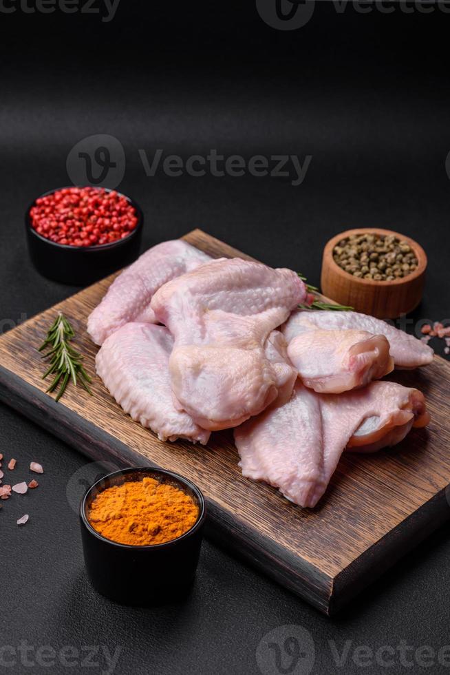 brut poulet ailes avec sel, épices et herbes sur une en bois Coupe planche photo