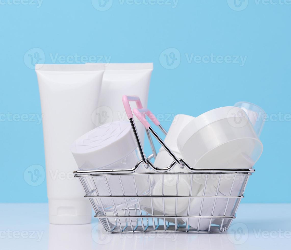 blanc Plastique tuyaux, pots dans une miniature métal panier, conteneurs pour cosmétique des produits. La publicité et promotion photo