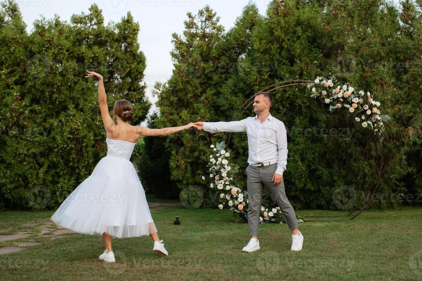 le premier Danse de le jeune marié et la mariée dans une court mariage robe sur une vert Prairie photo