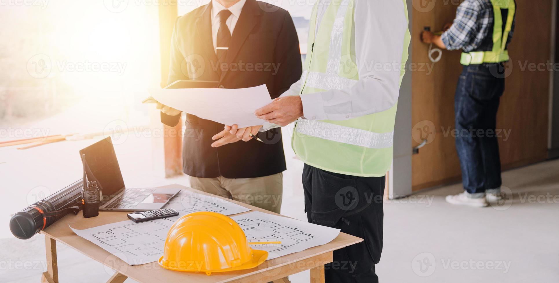 deux hommes d'affaires ingénieur de chantier. objets d'ingénierie sur le lieu de travail avec des partenaires interagissant en arrière-plan photo