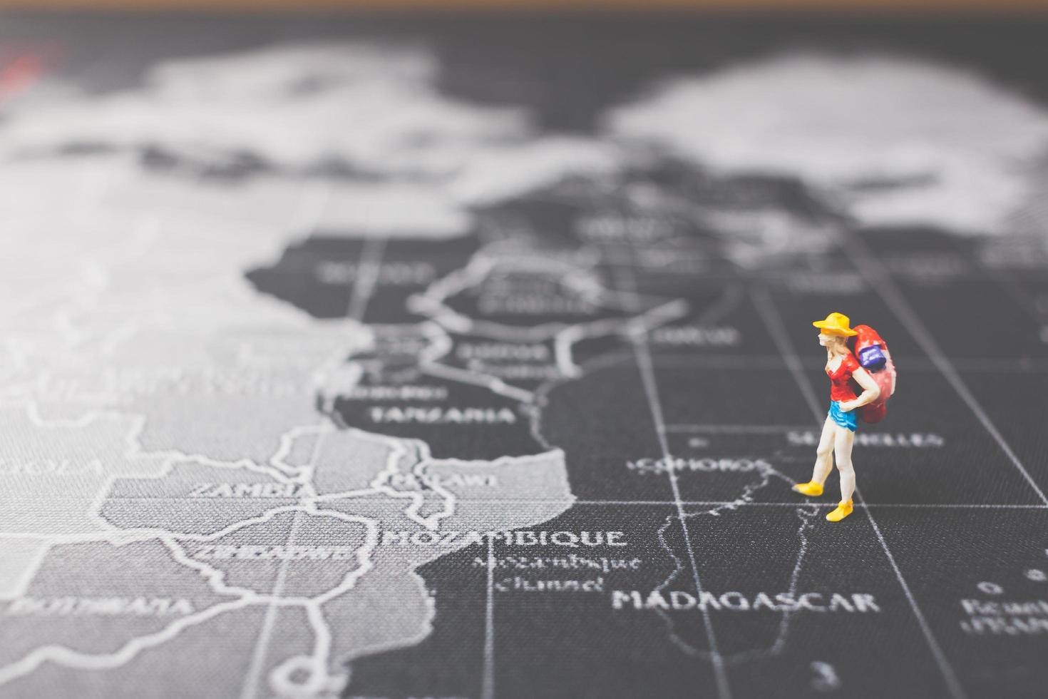 Routard miniature marchant sur une carte du monde, concept de tourisme et de voyage photo