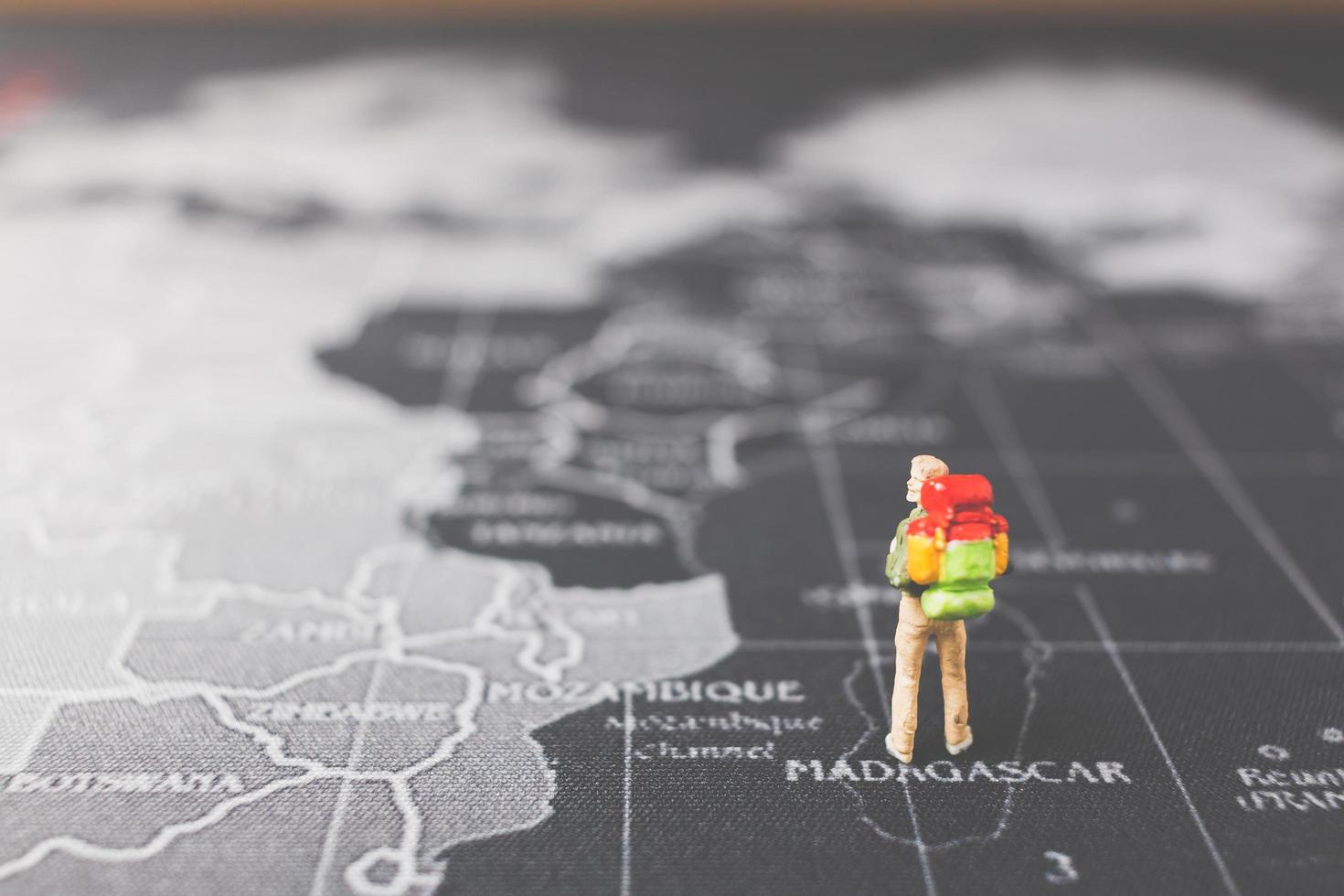 Routard miniature marchant sur une carte du monde, concept de tourisme et de voyage photo