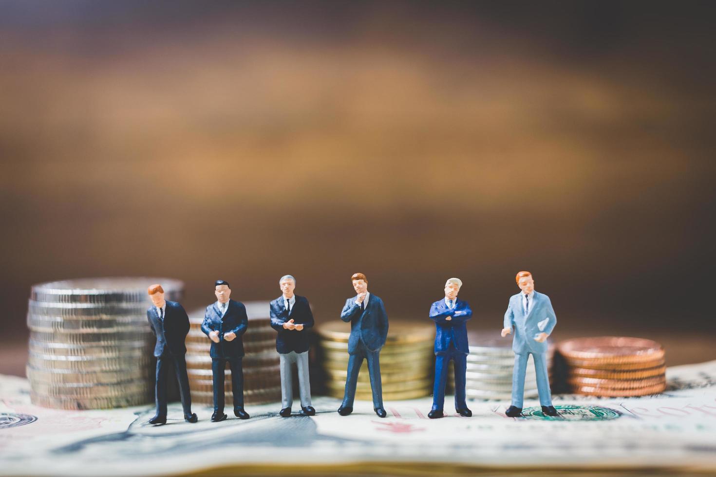 Hommes d'affaires miniatures sur de l'argent sur un fond de bois photo