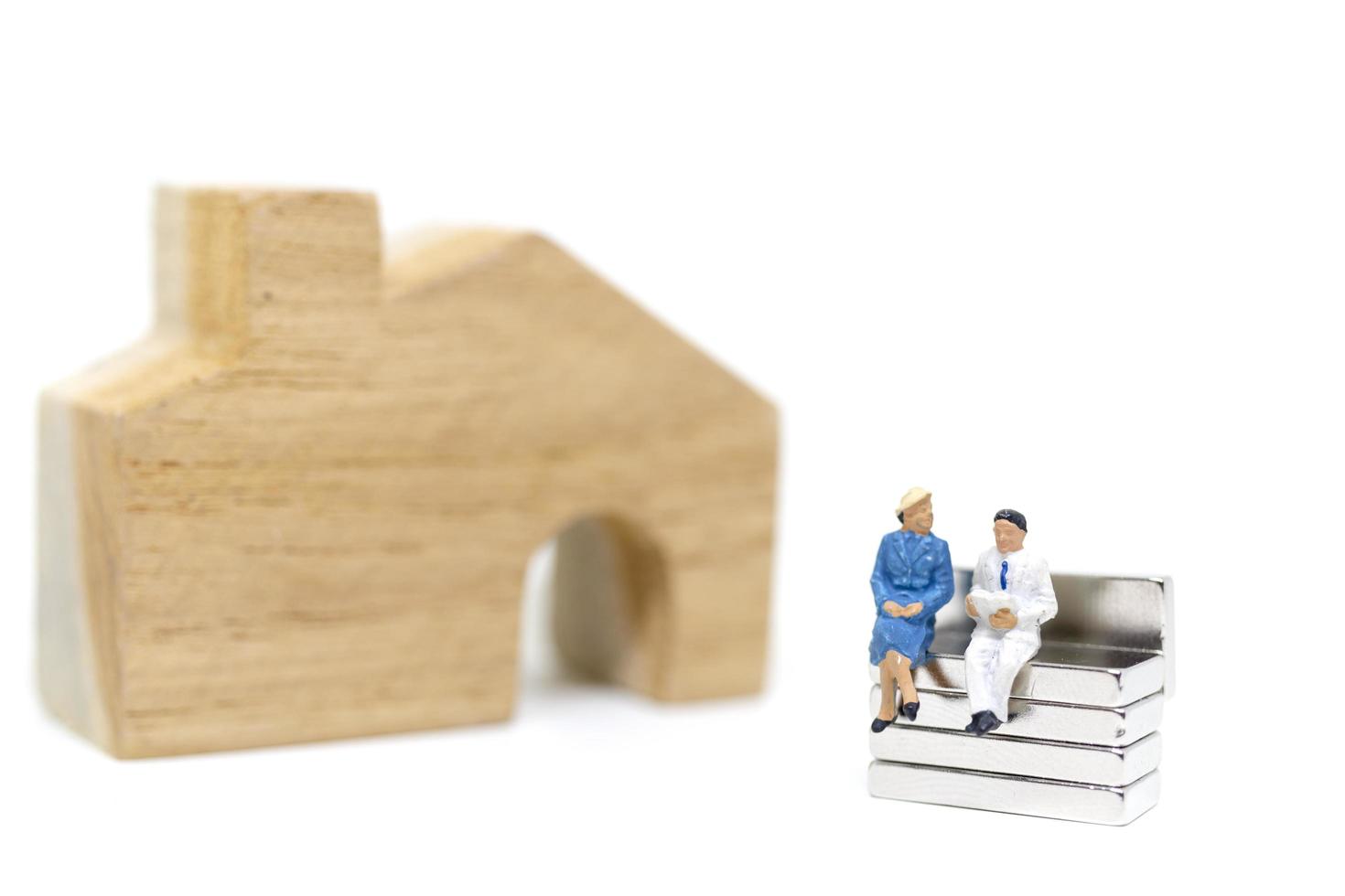 mari et femme miniature assis devant une maison sur un fond blanc, concept de famille photo