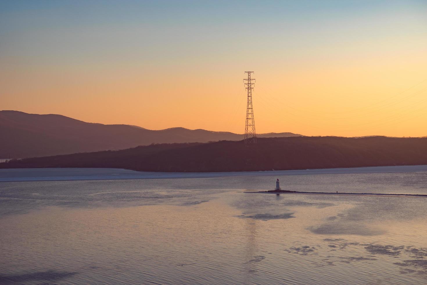 Paysage marin avec coucher de soleil sur le phare de tokarev et la baie de l'amour à vladivostok, russie photo