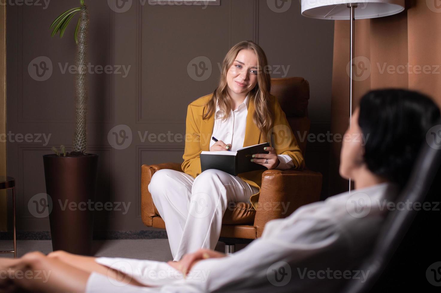 une Jeune femme fait du un entrée dans sa journal intime et regards à le client photo