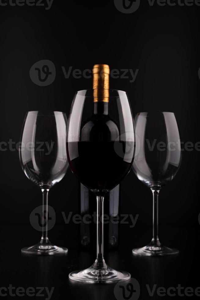 bouteilles de vin et verre plein avec fond noir photo