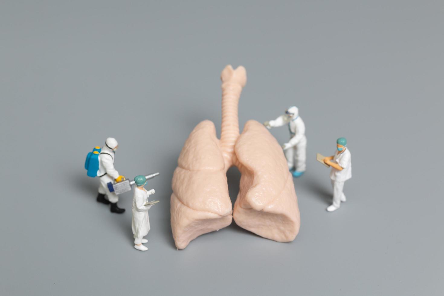 médecins et infirmières miniatures observant et discutant du concept infecté par les poumons, les virus et les bactéries photo
