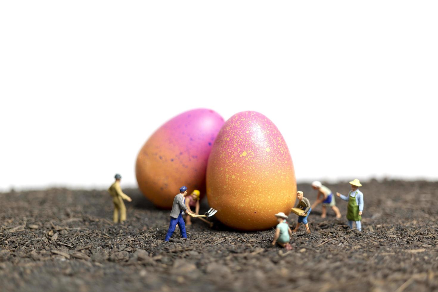 Les gens miniatures travaillant sur les oeufs de Pâques pour le jour de Pâques avec un fond blanc photo