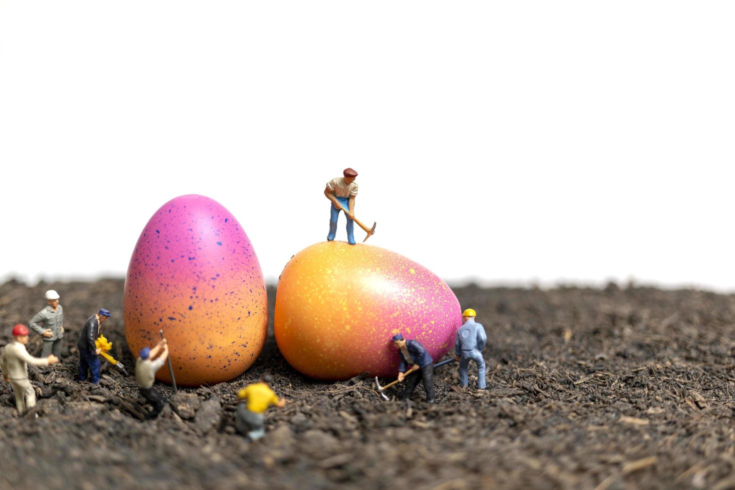 Les gens miniatures travaillant sur les oeufs de Pâques pour le jour de Pâques avec un fond blanc photo