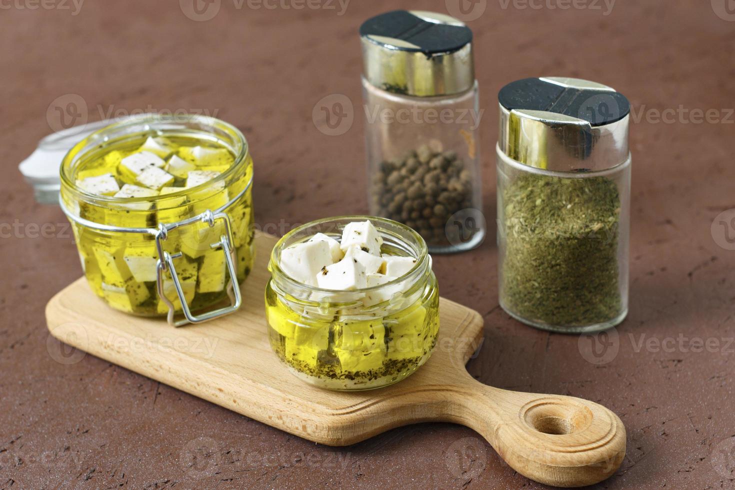 Feta marinée dans un bain en verre et épices sur fond de bois photo