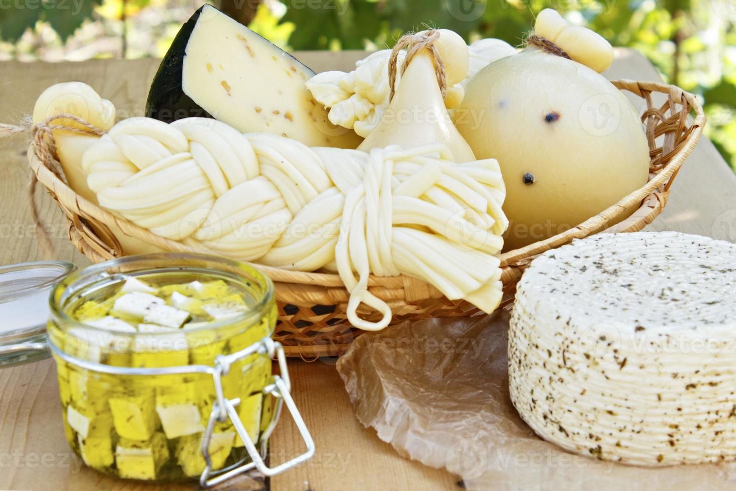 Différents types de fromages sur un fond en bois dans le contexte du feuillage vert photo