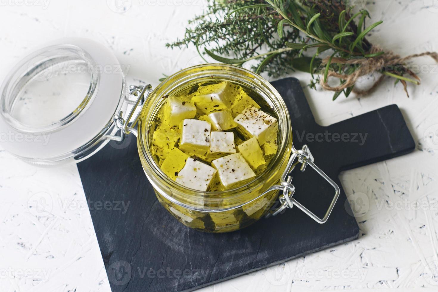 Feta marinée dans un bocal en verre et épices sur un fond blanc photo