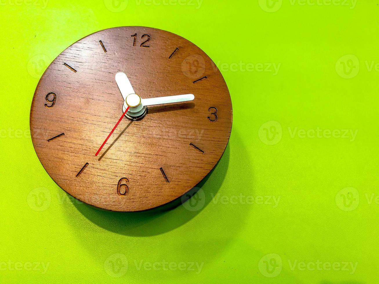 en bois mur l'horloge sur lumière vert cuir feuille. photo