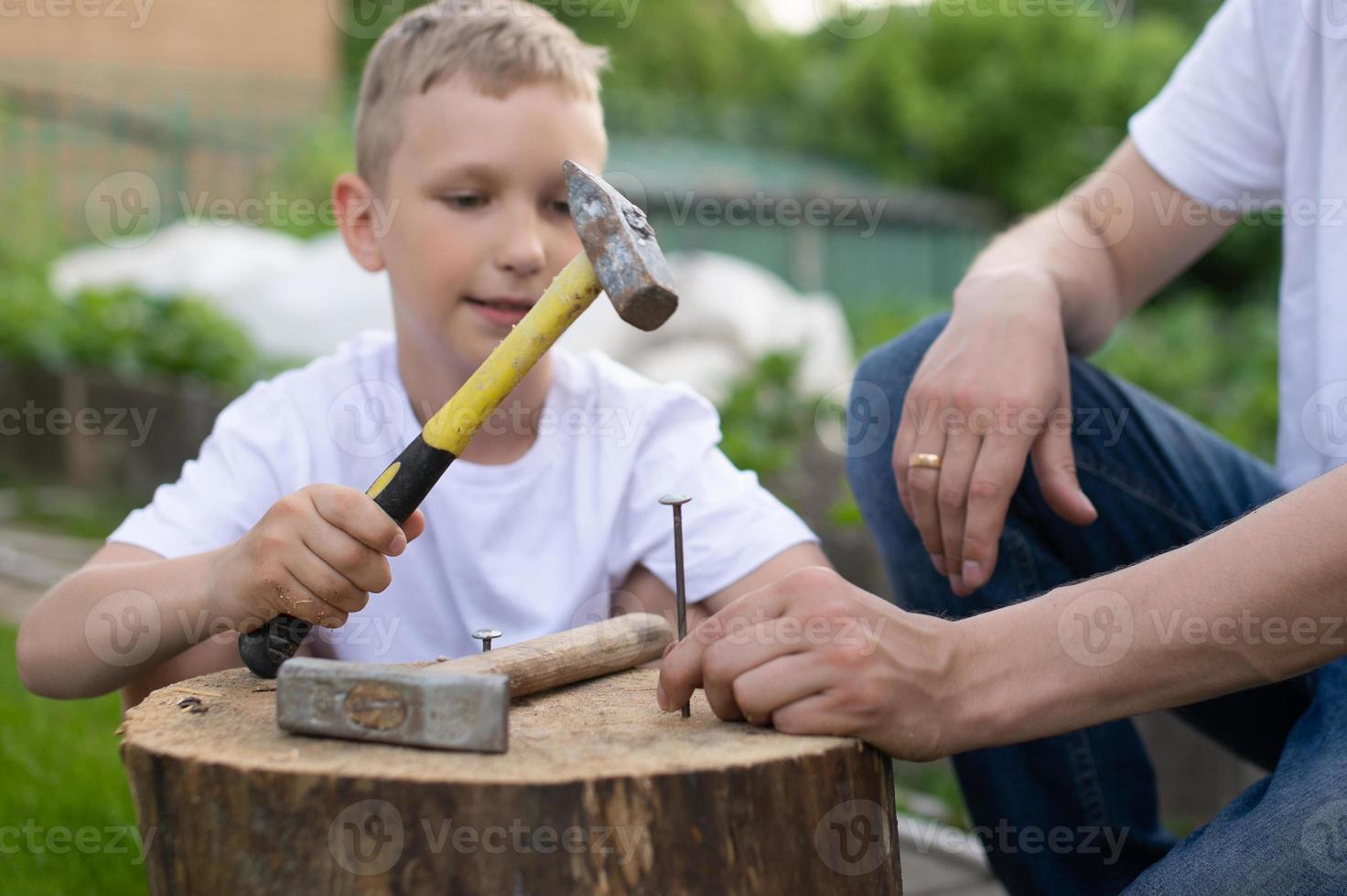 papa enseigne le sien fils à marteau ongles dans une arbre photo