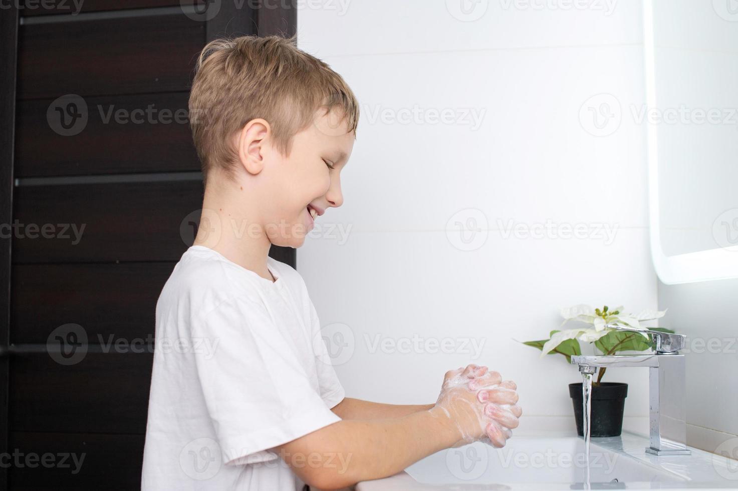 le mignonne garçon moussé le sien mains et sourit photo