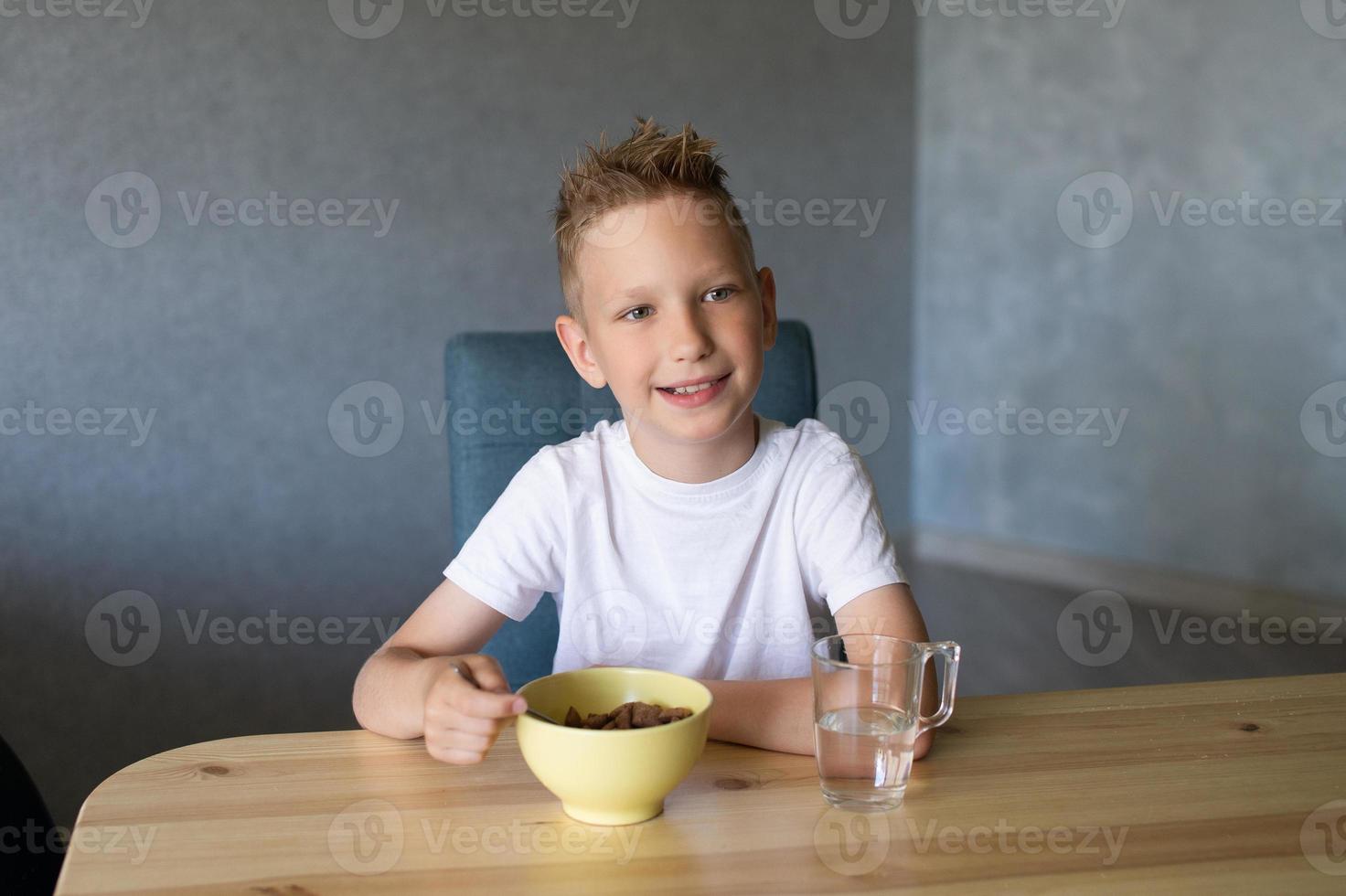 mignonne garçon mange une sec petit déjeuner à Accueil et sourit photo