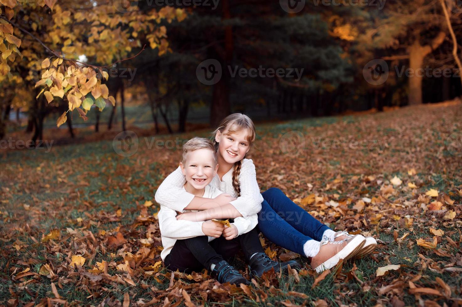 content fille et garçon lancer Jaune l'automne feuilles dans le forêt photo