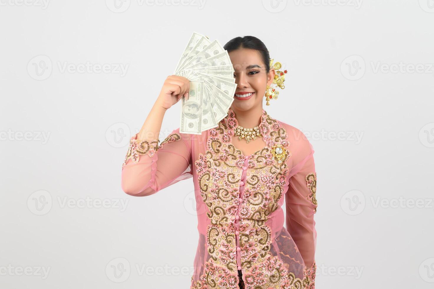 Jeune magnifique femme robe en haut dans local culture dans du sud Région pose avec billet de banque photo