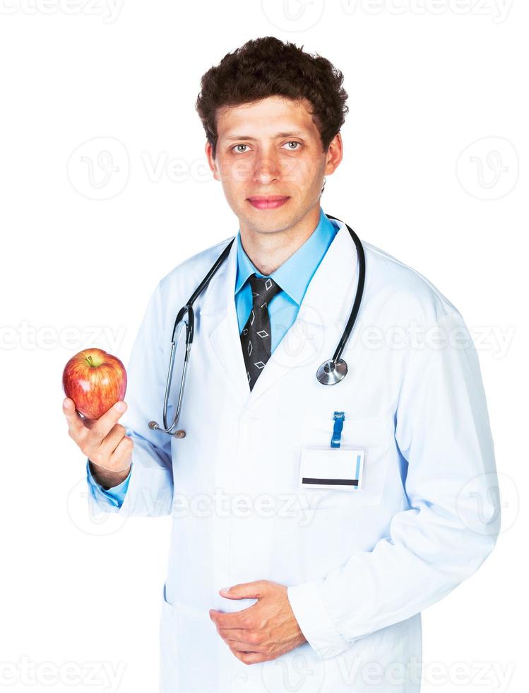 portrait de une souriant Masculin médecin en portant rouge Pomme sur blanc photo