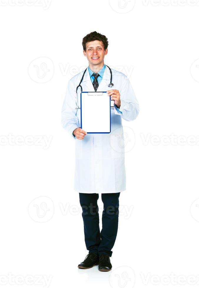 plein longueur Jeune souriant Masculin médecin montrant presse-papiers avec copie espace pour texte sur blanc photo