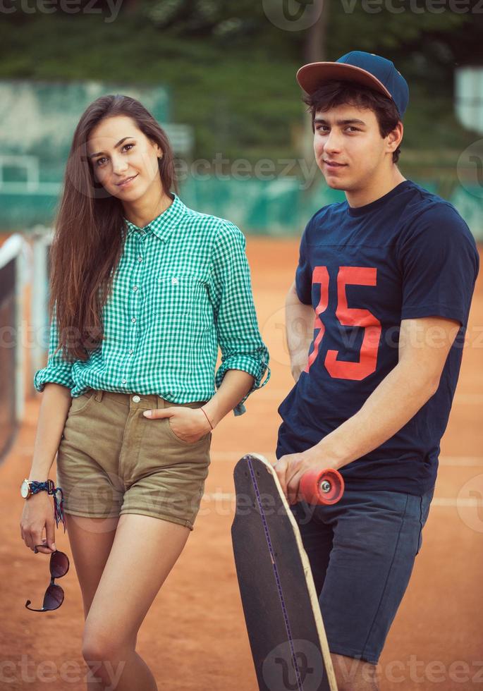 Jeune couple permanent sur une planche à roulette sur le tennis tribunal photo