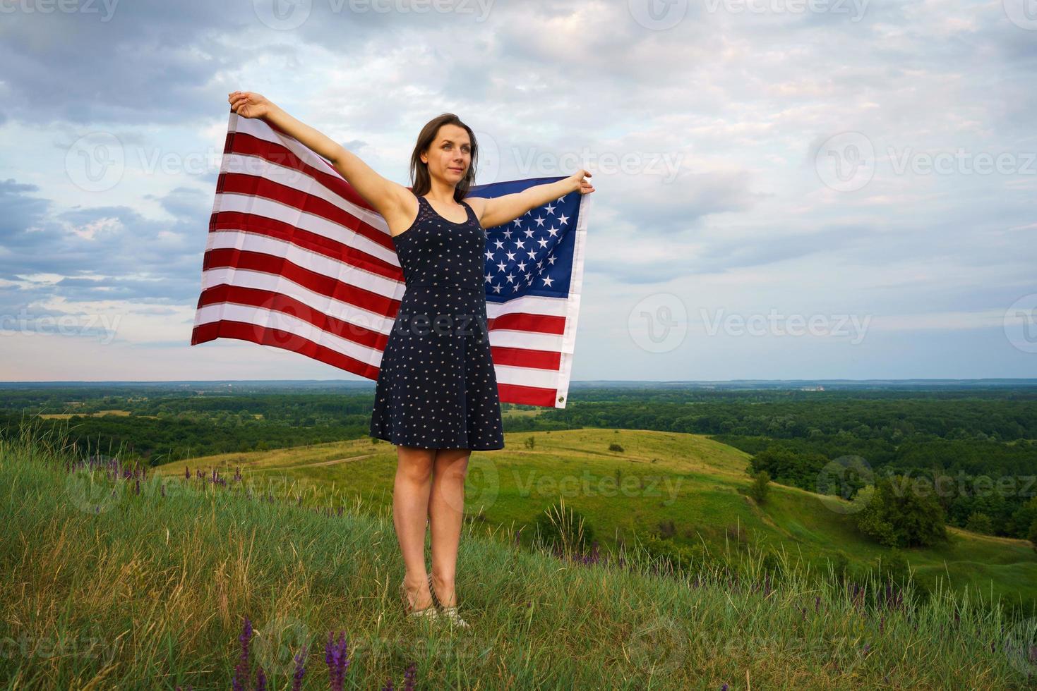 fier femme avec une nous drapeau est permanent sur Haut de une colline photo