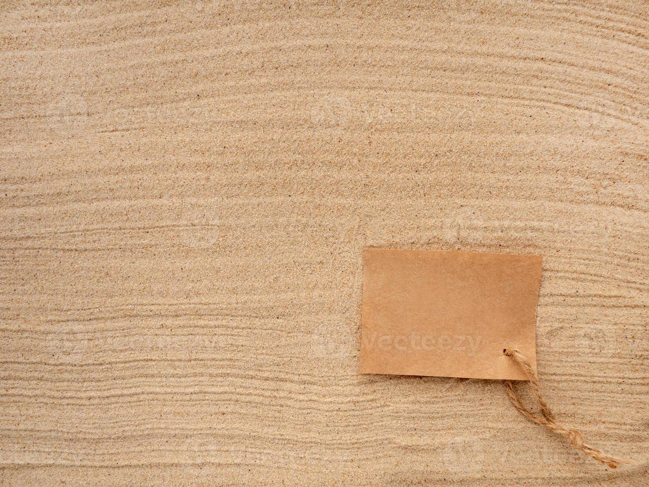 lettre dans le sable. artisanat papier avec ficelle sur le texture de mer sable. photo