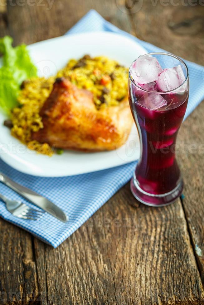 savoureux plat de poulet cuisse avec riz et salade et une verre de jus avec la glace photo