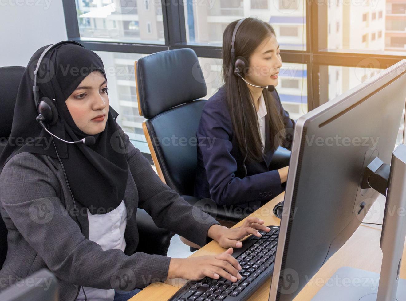 Les jeunes femmes musulmanes asiatiques travaillant au bureau sur l'ordinateur photo