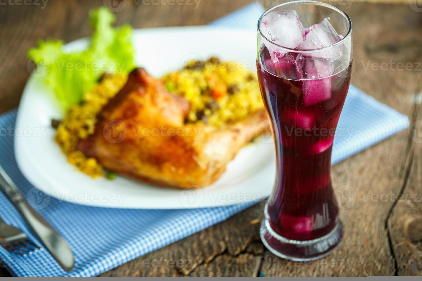 savoureux vaisselle de poulet cuisse avec riz et salade et une verre de jus avec la glace photo