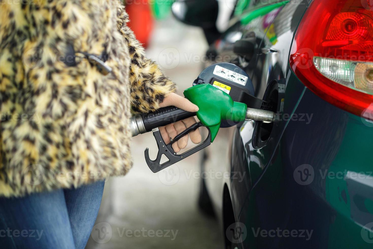 femme remplit essence dans sa voiture à une gaz station dans hiver photo