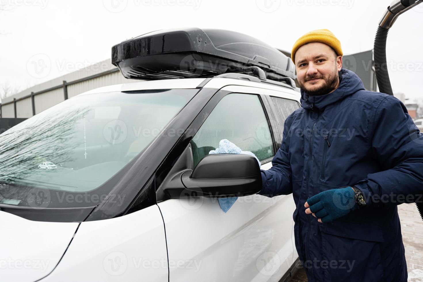 l'homme essuie la voiture suv américaine avec un chiffon en microfibre  après le lavage par temps froid. 21140545 Photo de stock chez Vecteezy