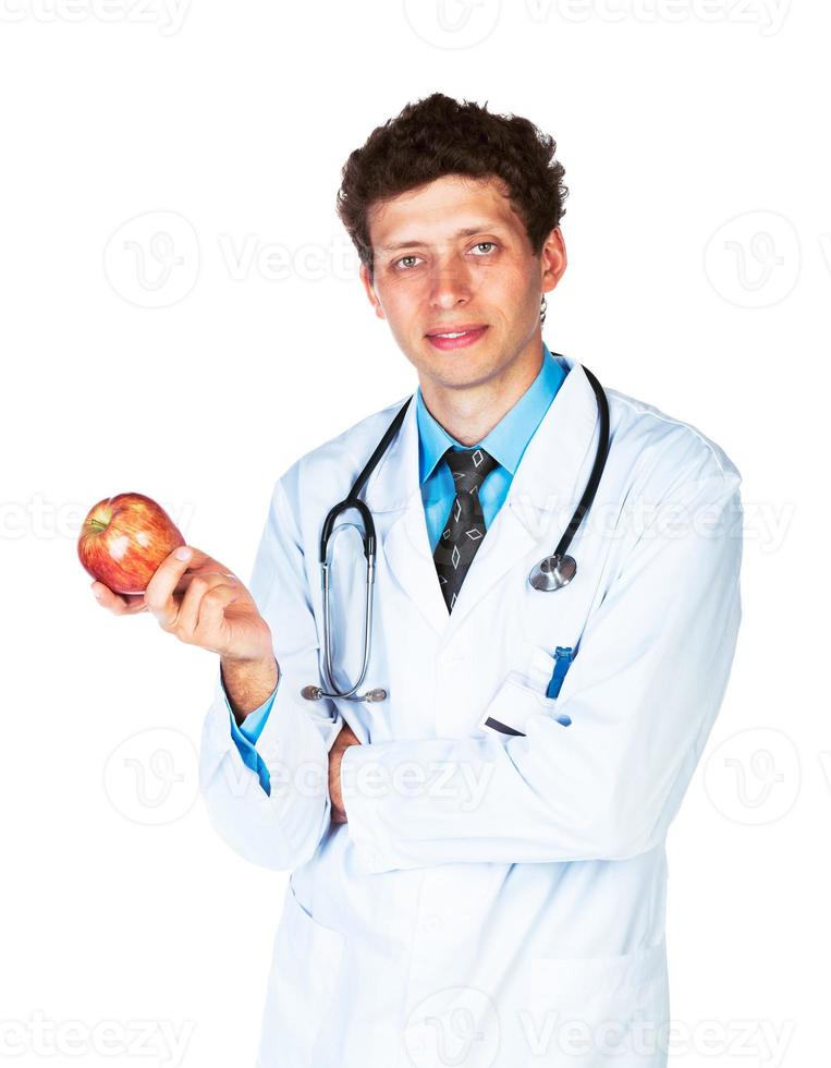 portrait de une souriant Masculin médecin en portant rouge Pomme sur blanc photo