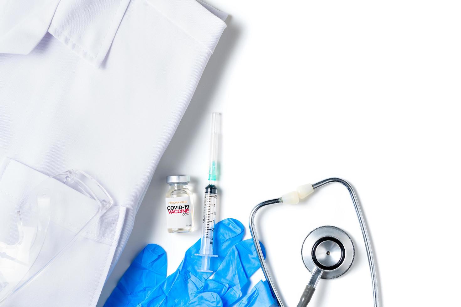 une Fiole de le convoitise 19 vaccin avec seringue et stéthoscope sur robe chemise isolé sur blanc arrière-plan, photo
