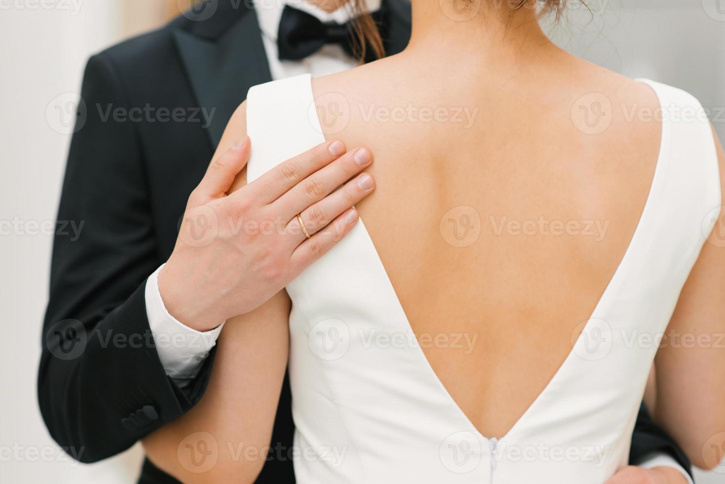 le jeune marié doucement et tendrement embrasse le la mariée par le épaules. fermer de le mains de une content couple photo