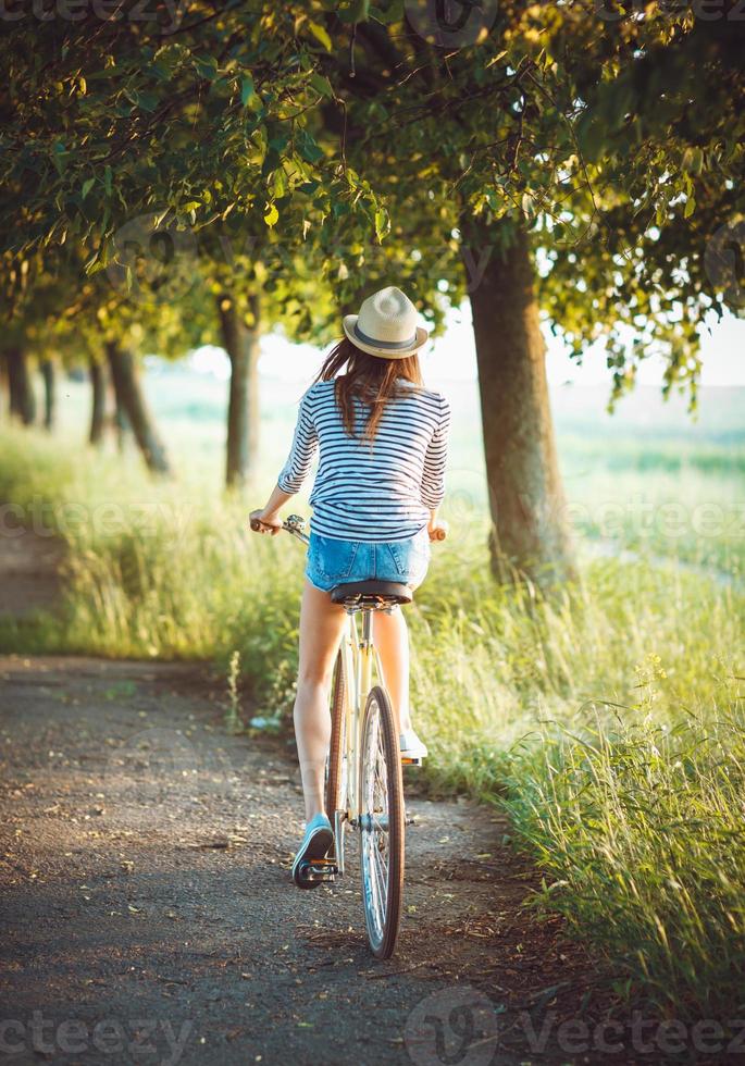 charmant Jeune femme dans une chapeau équitation une vélo en plein air. actif gens photo